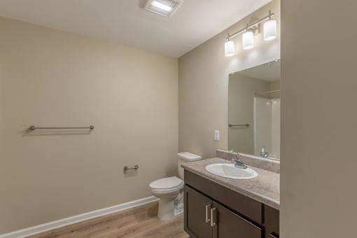 A bathroom with a toilet, sink, and mirror.