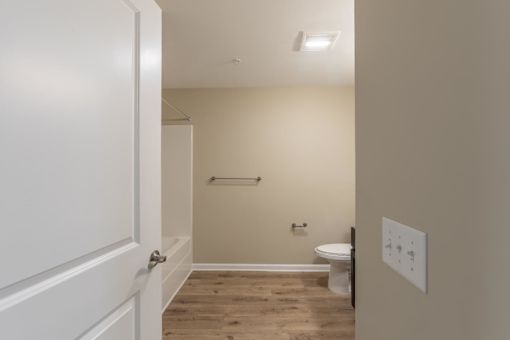 A white door is open to a small bathroom with a toilet and a sink.