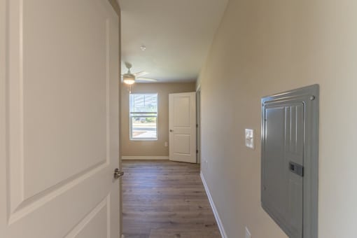 A long hallway with a door on the left and a window on the right.