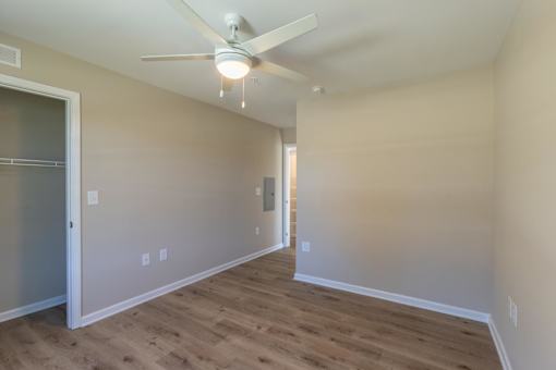 A room with a ceiling fan and wooden flooring.