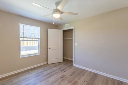 A room with a ceiling fan and a window with blinds.