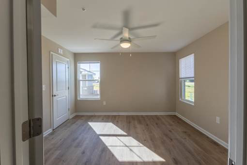 A room with a ceiling fan and wooden flooring.
