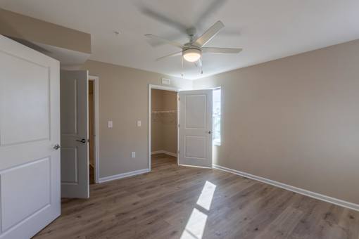 A room with a ceiling fan and light fixture, and a door to the left.