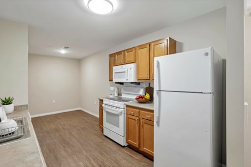 A kitchen with white appliances and wooden cabinets.