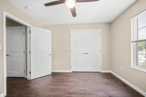 an empty living room with two doors and a ceiling fan