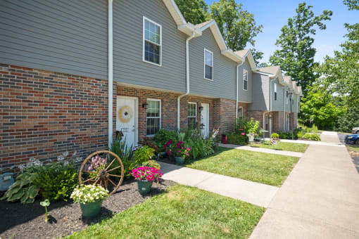 a front yard with flowers and a wagon wheel in front of a house