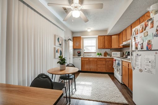A kitchen with a table and chairs in front of a refrigerator.
