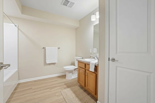 A bathroom with a toilet, sink, and mirror.