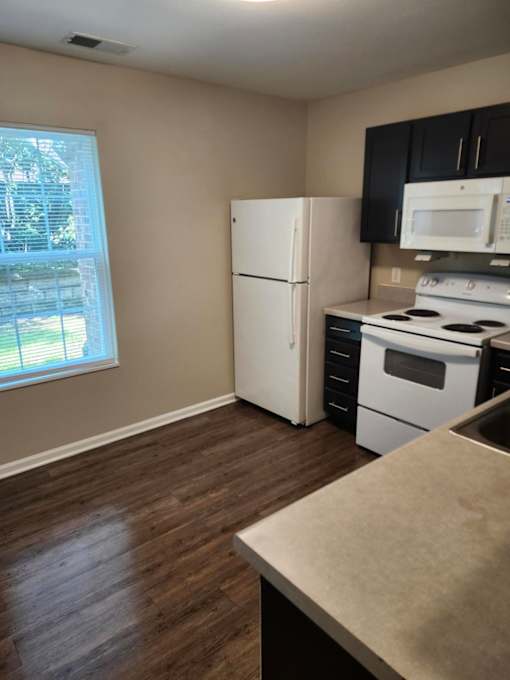 A kitchen with a white refrigerator, black cabinets, and a stove top oven.