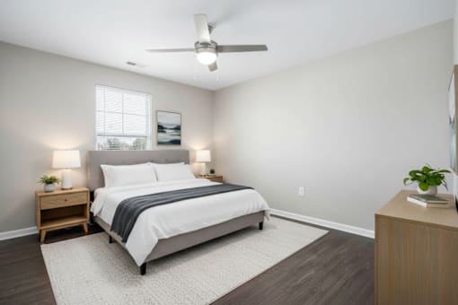 A bedroom with a bed, nightstands, and a ceiling fan.