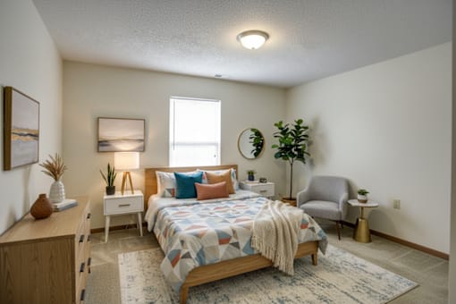 A bedroom with a bed, nightstand, and chair.