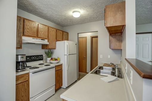 A kitchen with white appliances and wooden cabinets.