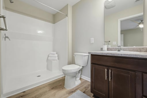 A white toilet sits in a bathroom next to a white bathtub.