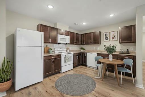 A kitchen with a white refrigerator, brown cabinets, and a wooden table.