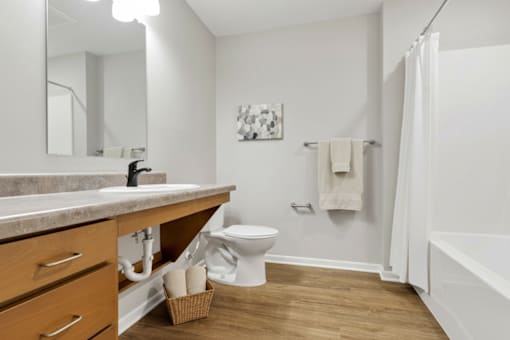 A white bathroom with a toilet, sink, and a white shower curtain.