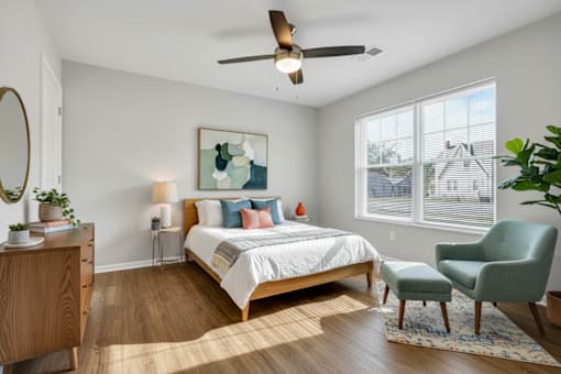 A bedroom with a bed, chair, and a painting on the wall.