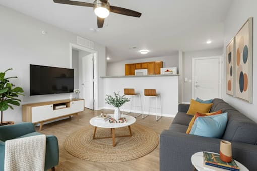 A living room with a grey couch, a wooden coffee table, a flat screen TV, and a ceiling fan.