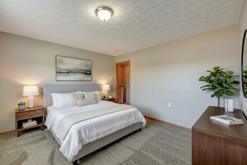 A bedroom with a large bed and a painting on the wall.