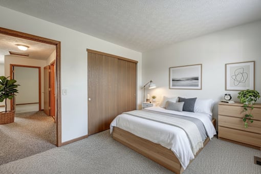 A bedroom with a large bed, a wooden dresser, and a mirror.