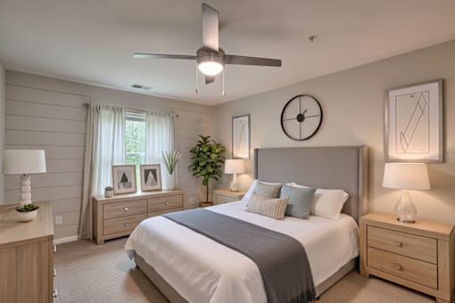 A bedroom with a bed, nightstands, and a ceiling fan.