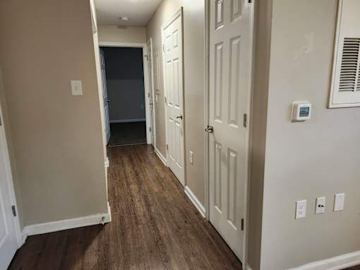 A hallway with wood flooring and white doors.