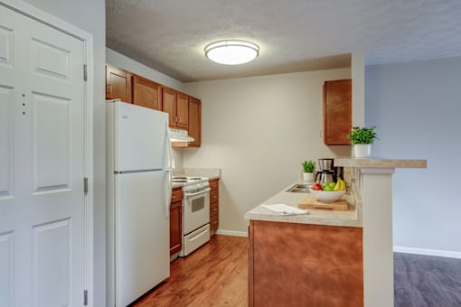A kitchen with a white refrigerator, wooden cabinets, and a copper island.