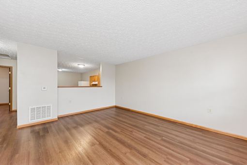 A room with wooden flooring and white walls.