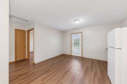 A room with wooden floors and a white refrigerator.