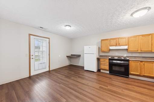 A kitchen with wooden floors and white appliances.