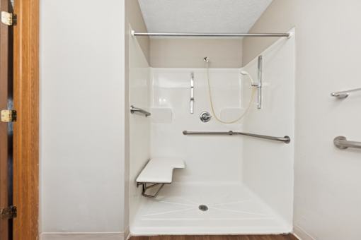A white shower stall with a bench and a shower head.