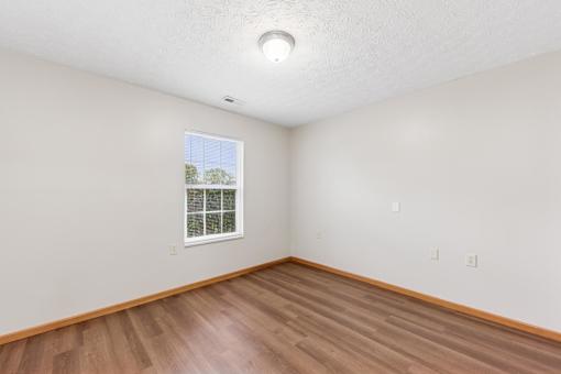 A room with a window and wooden flooring.