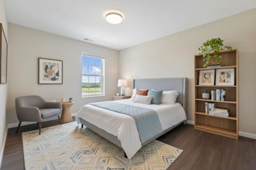 A bedroom with a bed, a chair, and a bookshelf.