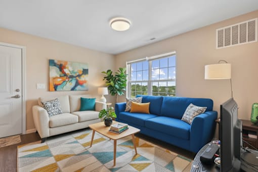 A living room with a blue couch, a coffee table, and a painting on the wall.