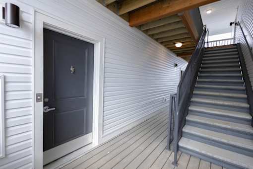 A staircase with a dark grey door and white walls.