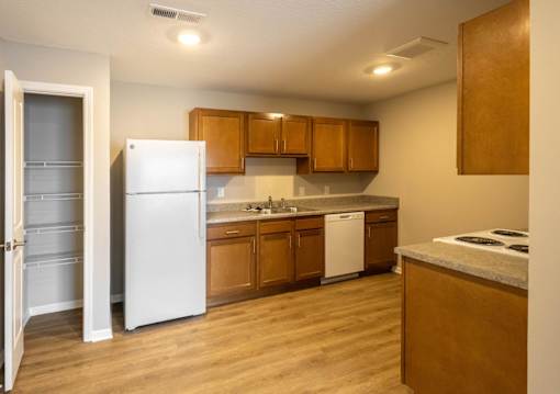 A kitchen with a white refrigerator and wooden cabinets.