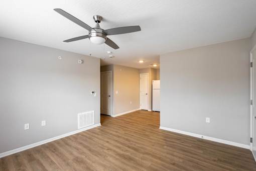 A room with a ceiling fan and wooden flooring.