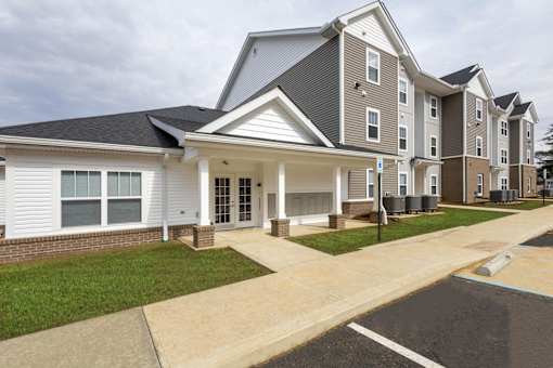 A large apartment complex with multiple buildings and a driveway in front.
