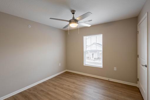 Empty room with a ceiling fan and a window.