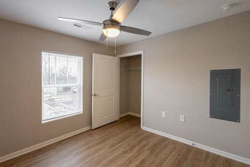 A room with a ceiling fan and a door leading to another room.