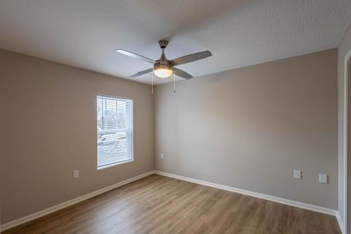 Empty room with a ceiling fan and a window.