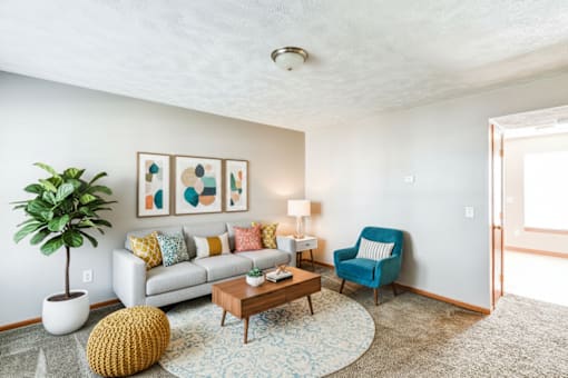 A living room with a couch, chair, and potted plant.