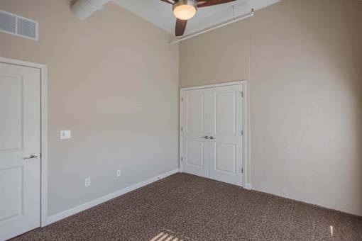 A room with a carpeted floor and a ceiling fan.