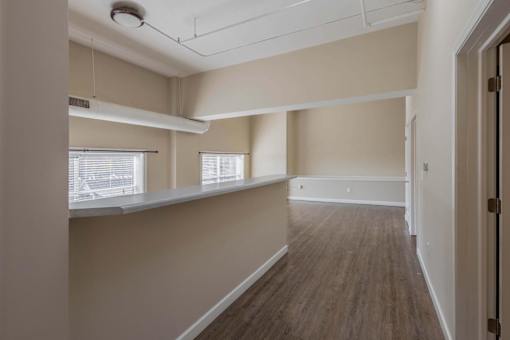 A long, empty hallway with wooden floors and white walls.