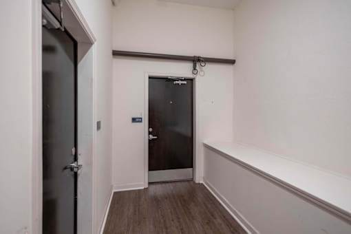 A hallway with a door at the end and a wall on the right.