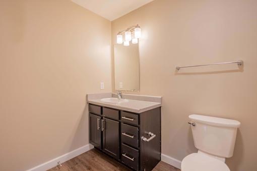 A bathroom with a white toilet and a sink with a cabinet underneath it.