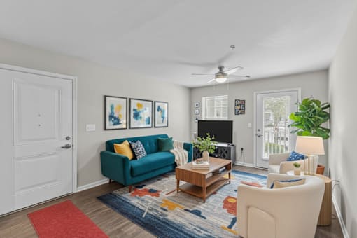 A living room with a blue couch, a red rug, and a ceiling fan.