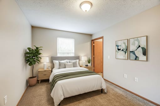 A bedroom with a bed, nightstands, and a plant.