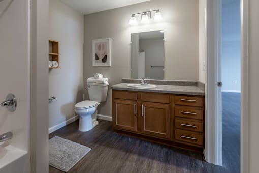 A bathroom with a toilet, sink, and mirror.