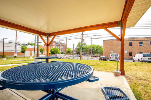 a picnic area with a table and benches and a building in the background
