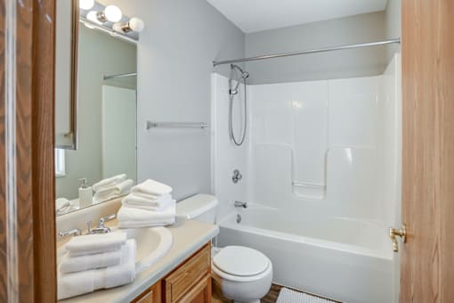 A white toilet sits next to a white bathtub in a bathroom.